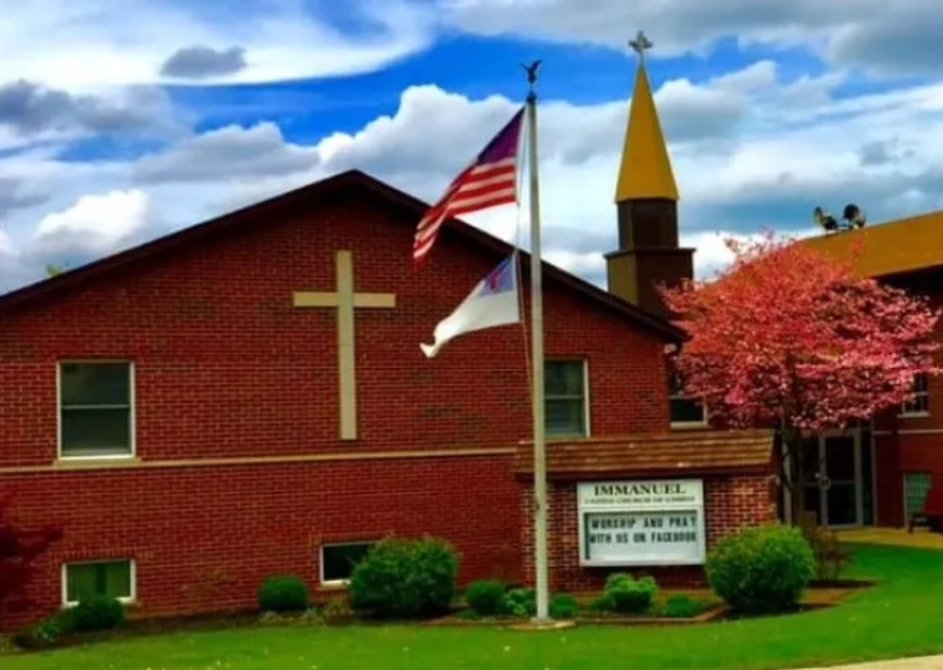 Immanuel church, red brick with cross on wall and American flag in front